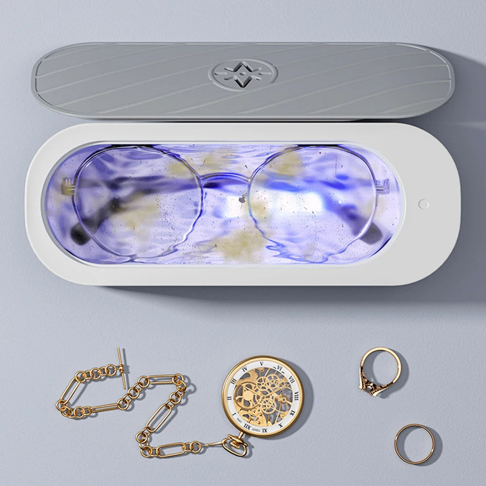 Nettoyeur à ultrasons compact avec lunettes et petits bijoux dans le bac de nettoyage